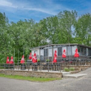 Brown exterior of Mississippi Pub with their patio with red umbrellas